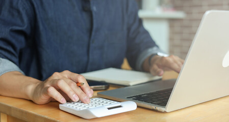 man hand use on calculator to check about debt bills pay monthly at the table in home and manage expense payroll for financial lifestyle concept