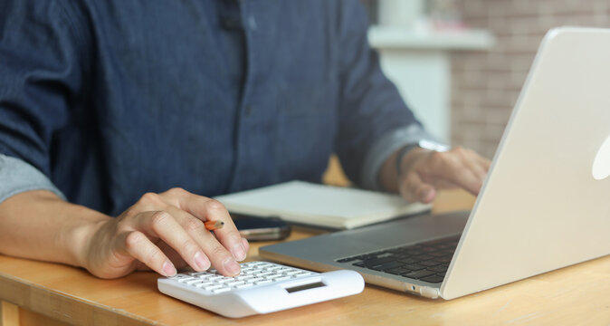 man hand use on calculator to check about debt bills pay monthly at the table in home and manage expense payroll for financial lifestyle concept