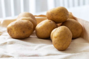 Potatoes lying on the table and white chairs in the background.