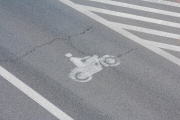 Bicycle symbol painted in white on dark asphalt creates clear cycling lane marking for urban bike path designation