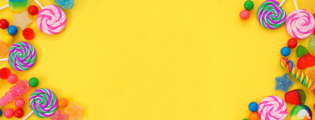 Colorful collection of candies. Above view double border over a yellow banner background.