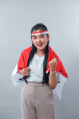 Indonesian woman with a red and white flag on her shoulders, smiling confidently while showing a...