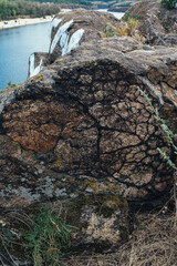 A fragment of a red-gray stone rock close-up with black veins, the stone breed has sharp edges, a large stone on the right, summer, veins of stone