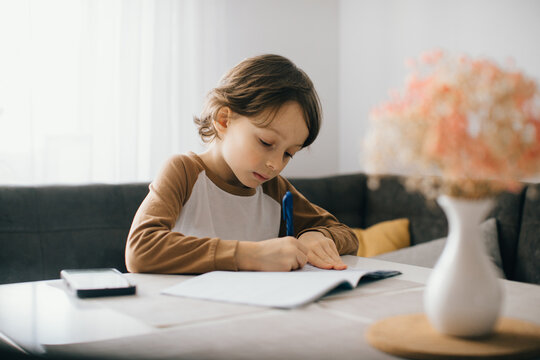 Child doing homework at home writing on notebook at the table