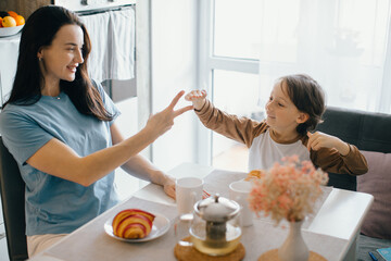 Mother and son playing rock paper scissors during breakfast in kitchen