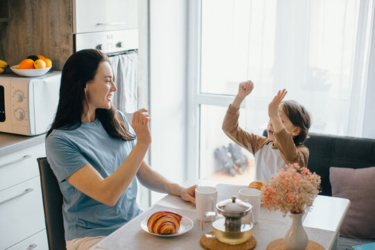 Mother and son dancing and having fun during breakfast in the kitchen