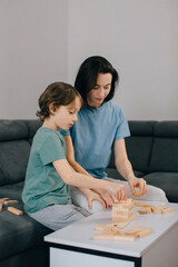 Fototapeta premium Mother and son building tower with wooden blocks at home