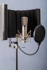 Studio microphone on a holder with a pop filter and a curtain on a gray background in a recording studio