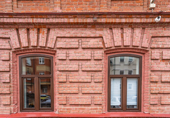 Two windows of the old mansion 19 century with brown bricks wall
