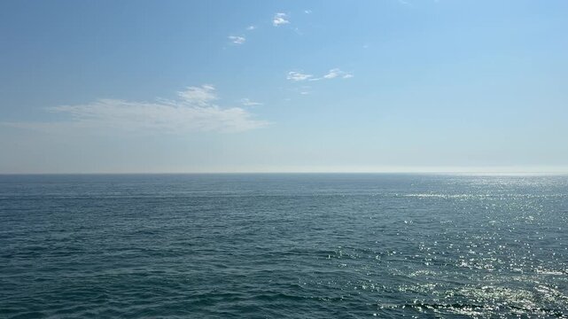 Blue sea sparkling surface and clear sky.