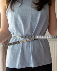 girl in sportswear measures waist size. concept of fighting excess weight and obesity, social...