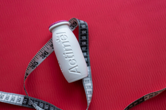 Warsaw, Poland, 07 27 2025:  close-up of a jar of Actimel yogurt next to a measuring tape. abstraction on the topic of proper nutrition and weight loss, the fight against excess weight and obesity