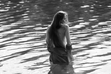 Elegant woman in red dress, back view by the lake