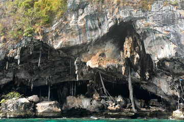 Viking Cave in Thailand, a large sea cave in a limestone cliff with turquoise waters front.