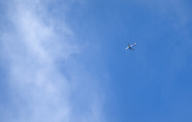 Passenger airplane flying high in a clear blue sky with soft clouds. Ideal for travel, aviation, business trips, and transportation projects.  Clean and dynamic aviation imagery.