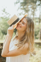 Tourist holding a straw hat and smiling in nature