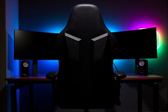 Ultimate gamer setup with an ergonomic chair, dual monitors, and colorful RGB lighting creates a professional command center for streaming or esports competition