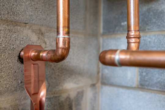Soldered copper pipe plumbing connections and fittings for new potable water pipes in a bathroom.