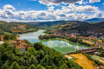 Panoramic aerial drone view of the medieval village of Sassocorvaro above the Mercatale dam, in the province of Pesaro Urbino, Marche, Italy. The village exudes peace, serenity, and ancient history.