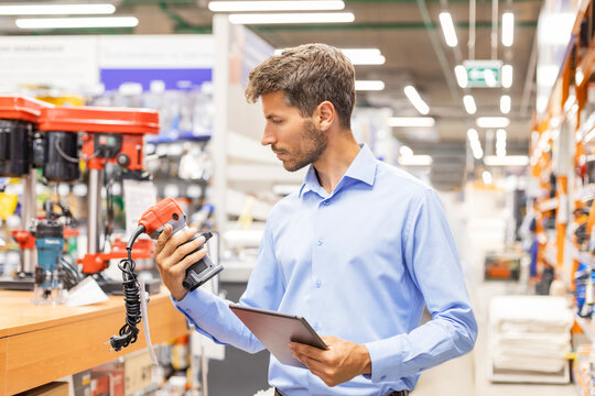 warehouse employee studies goods in a hardware store and checks the availability of goods on a digital tablet.