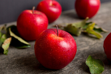 Fresh red apples with green leaves on wooden table. On wooden background. Top view free space for text