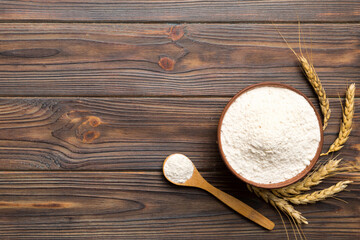 Flat lay of Wheat flour in wooden bowl with wheat spikelets on colored background. world wheat crisis
