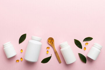 Omega-3 capsules lie in white bottle on a table with green leaves background. Fish oil tablets. Biologically active additives. omega 6, omega 9, vitamin A, E, D, vitamin D3 top view with copy space