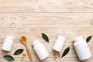 Omega-3 capsules lie in white bottle on a table with green leaves background. Fish oil tablets. Biologically active additives. omega 6, omega 9, vitamin A, E, D, vitamin D3 top view with copy space