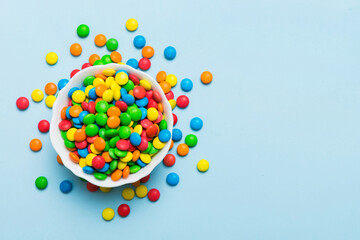 Multicolored candies in a bowl on a colored background. birthday and holiday concept. Top view with copy space