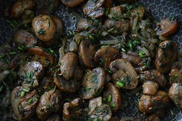 A high-angle view of a pan filled with beautifully cooked mushrooms, garnished with finely chopped fresh herbs, highlighting the rich colors and textures of the dish