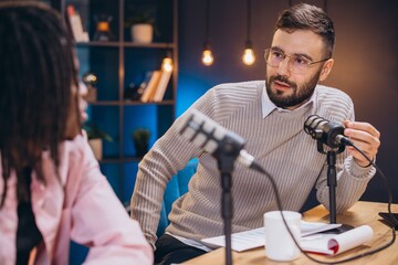 Podcasters discussing content while recording audio in professional broadcasting environment