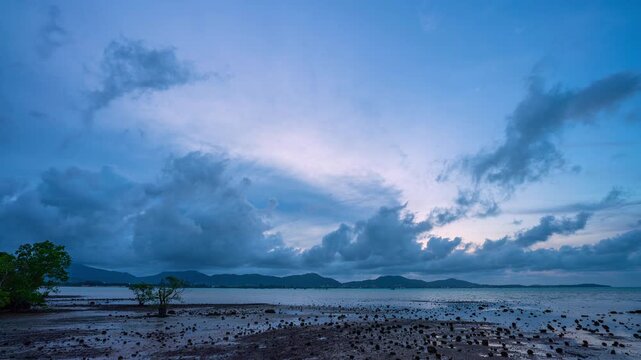 Time lapse Cloud Moving in Bluesky over the mudflat in mangrove forest during sunset The scene captures the peaceful transition between day and night along a serene shoreline.