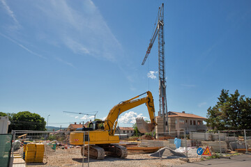 Excavator and tower crane at construction site