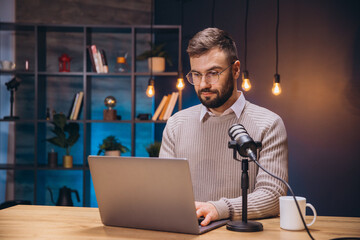 Young man recording a podcast in a home studio, using a laptop and microphone to create engaging audio content for online audiences