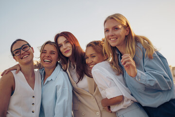 A joyful group of friends happily smiling together, enjoying the warm sun on a beautiful day