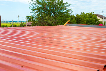 Surface view of roofing metal sheet painted with red paint. Materials for roof construction