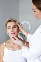 Facial plastic surgeon preparing patient for facelift surgery in medical clinic. Cosmetic face...