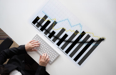 A business professional reviews financial data presented in a graphical format while typing on a...