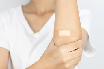 Close up of a plaster on an arm after a blood test or blood donation. Patient's arm with a bandage after a medical checkup or vaccination injection.