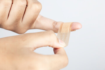 Applying adhesive plaster to an injured finger. First aid and wound care concept. Hands preparing a bandage for a cut or minor injury from a home accident.