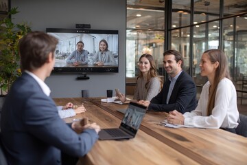 Hybrid team meeting in modern office with video conference technology connecting remote participants