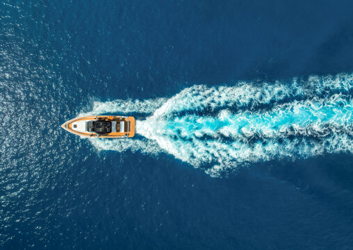 Aerial view of speed boat in crystal clear turquoise water at sunset. Summer in Mallorca, Balearic Islands, Spain, Top drone view of luxury yacht, blue sea in sunny day. Tropical landscape. Travel