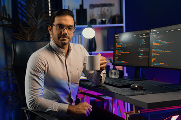 Profile smart IT developer looking camera holding coffee cup against on software development coding...