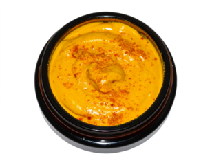 Vibrant golden turmeric paste with paprika spice dusting in a dark jar, perfect for culinary inspiration