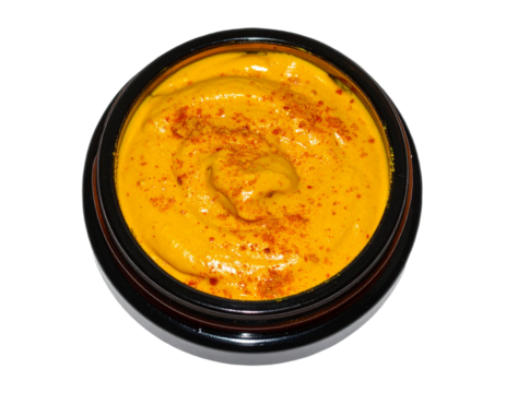 Vibrant golden turmeric paste with paprika spice dusting in a dark jar, perfect for culinary inspiration