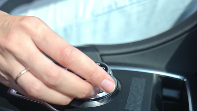 Close-up of hand turning gear shift knob in modern car interior. Driver switches transmission in parking mode on automatic gearbox