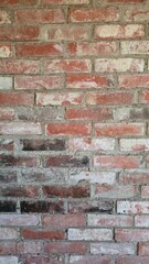 Close-up of an old and weathered red brick wall with visible mortar and uneven patina. Ideal for use as a textured background in design, construction themes, or rustic and industrial style interiors.