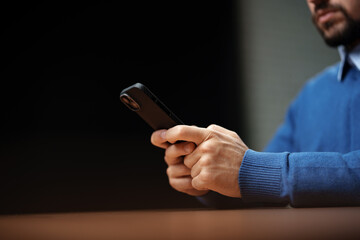 Man using smartphone indoors while sitting at a table in a casual setting