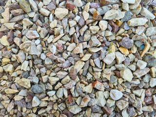Close-up of a colorful gravel surface, showcasing various sizes and shapes of stones. Ideal for backgrounds in construction or landscaping projects.