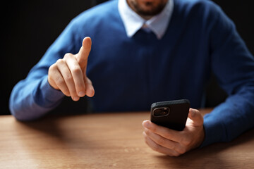 Person engaged in conversation using a smartphone while sitting at a wooden table during an indoor setting